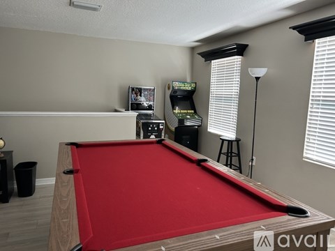 A pool table is in the middle of a room with a TV and a stand.