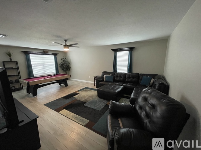 A living room with a black leather couch and a wooden floor.