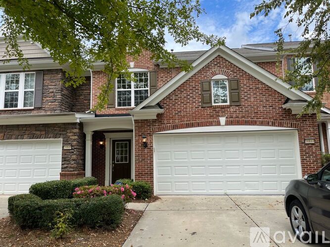 A house with a brick facade and two white garage doors.