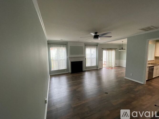 A spacious living room with wood flooring and a ceiling fan.