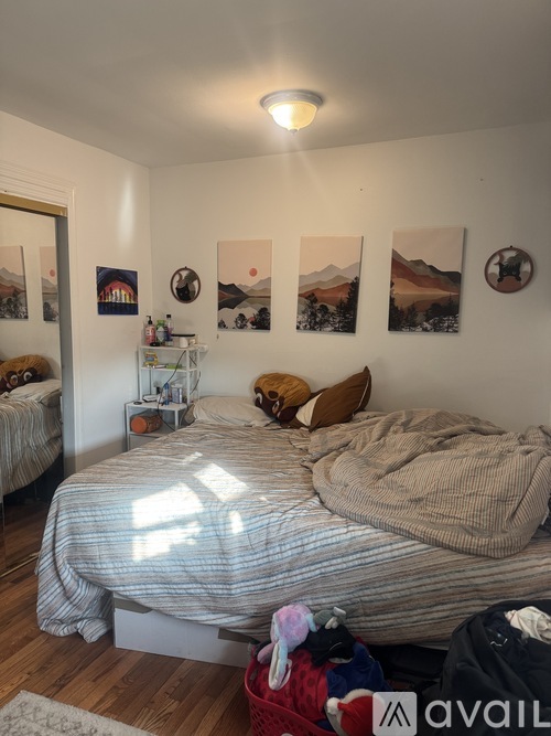A bedroom with a bed, pillows, and pictures on the wall.