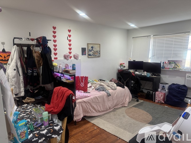 A messy bedroom with a bed, desk, and cluttered closet.