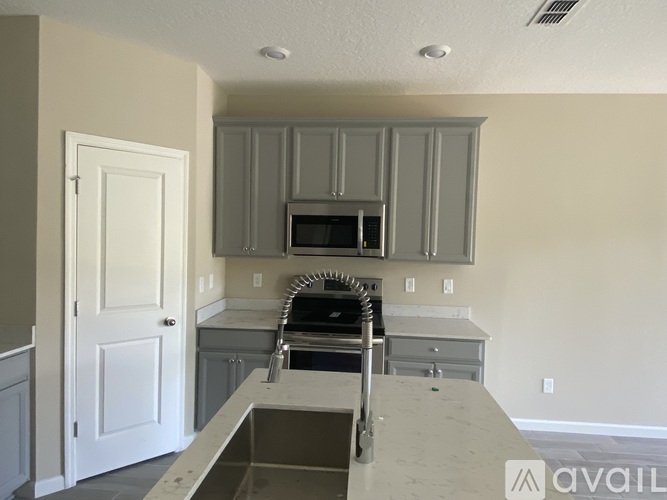 A kitchen with a white door and a microwave above the stove.