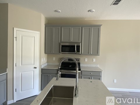 A kitchen with a white door and a microwave above the stove.