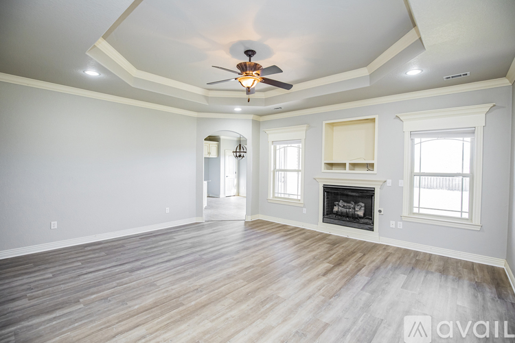 A spacious living room with a fireplace and a ceiling fan.