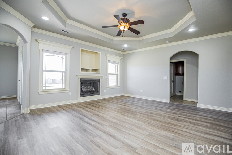 A spacious room with a fireplace and a ceiling fan.