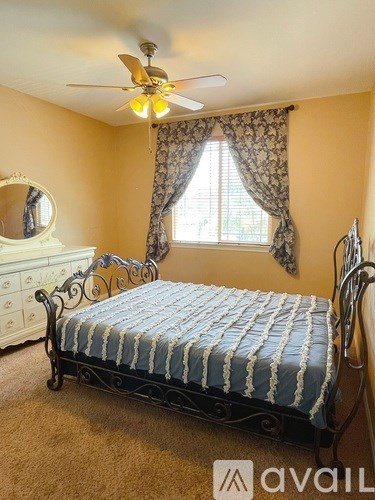 A bedroom with a bed, dresser, and window.