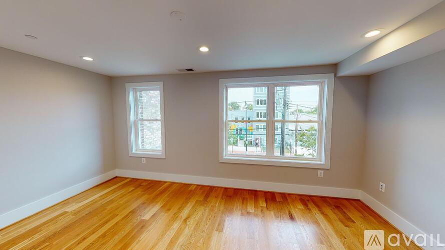 A room with wooden floors and two windows.