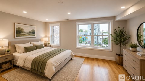 A room with wooden floors and white walls, with a window showing a view of a building and trees.