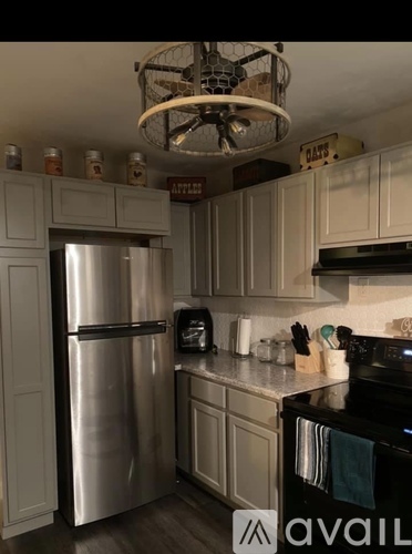 A kitchen with a stainless steel refrigerator and wooden cabinets.