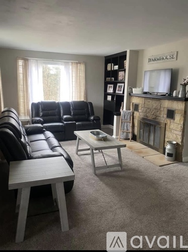A living room with a black leather couch and a fireplace.