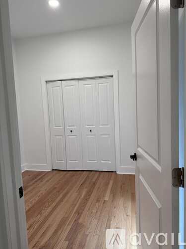 A white door with a black handle is in a room with wooden flooring.