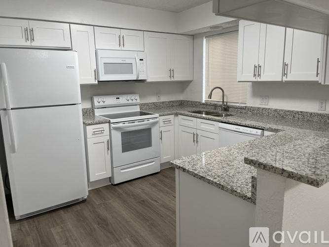 A kitchen with white appliances and cabinets.