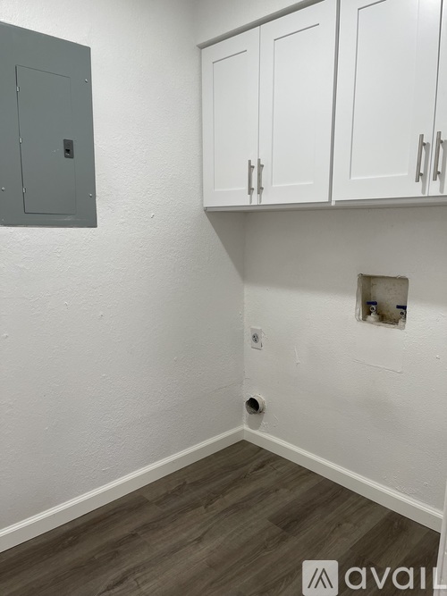 A grey metal box is mounted on a white wall next to a white cabinet.