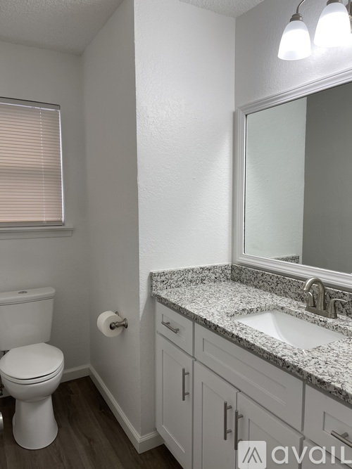 A bathroom with a toilet, sink, and mirror.