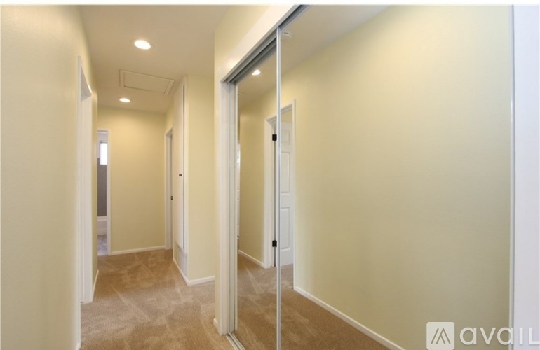 A hallway with a carpeted floor and white walls.