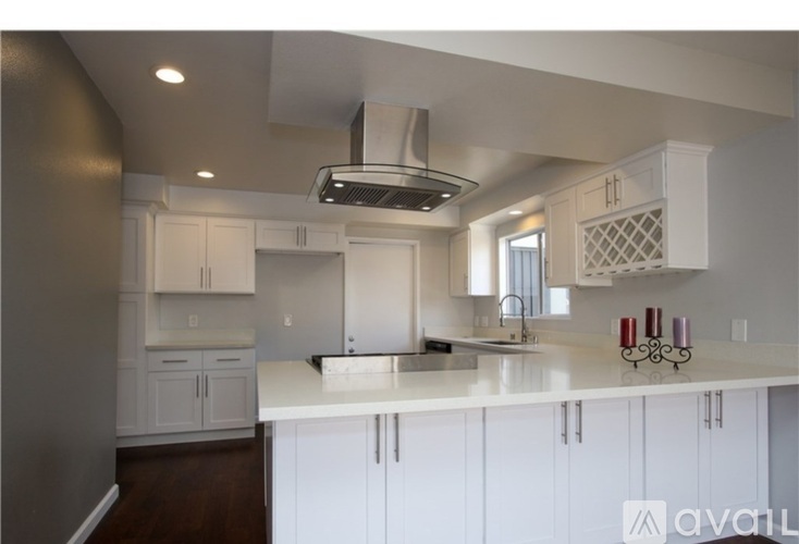 A kitchen with white cabinets and a stainless steel range hood.