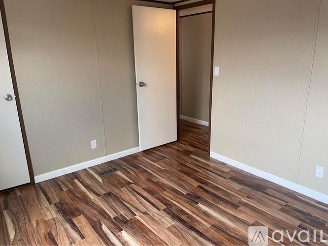 A room with wood flooring and a white door.