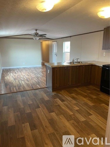 A kitchen with wooden floors and a ceiling fan.