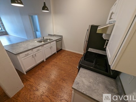 A kitchen with white cabinets and a wooden floor.