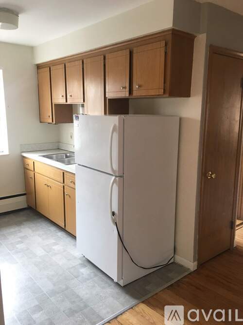 A white refrigerator in a kitchen with wooden cabinets.