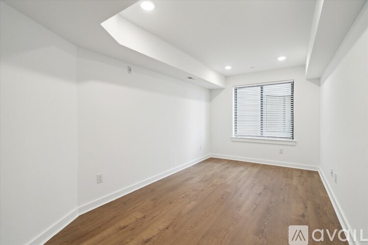 A room with wooden flooring and a window with blinds.