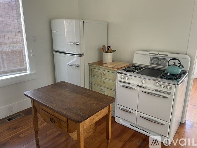 A kitchen with a white fridge, a white stove, and a wooden table.