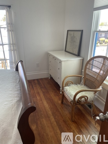 A bedroom with a bed, chair, and cabinet.