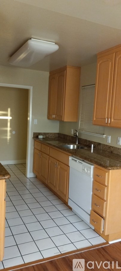 A kitchen with wooden cabinets and a white dishwasher.