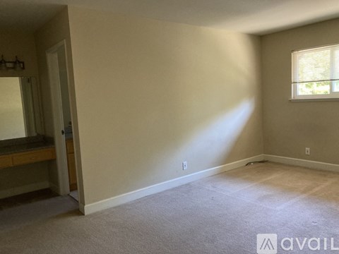 A room with a carpeted floor and a window with blinds.