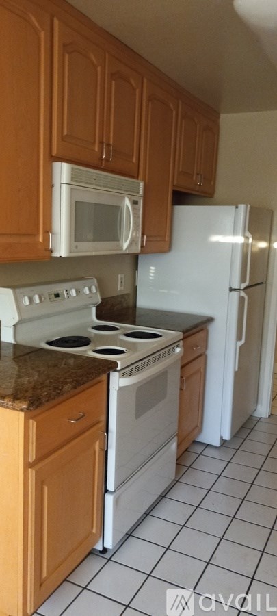 A kitchen with white appliances and brown cabinets.