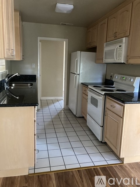 A kitchen with white appliances and wooden cabinets.