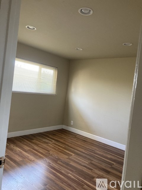A room with wooden flooring and a window with blinds.