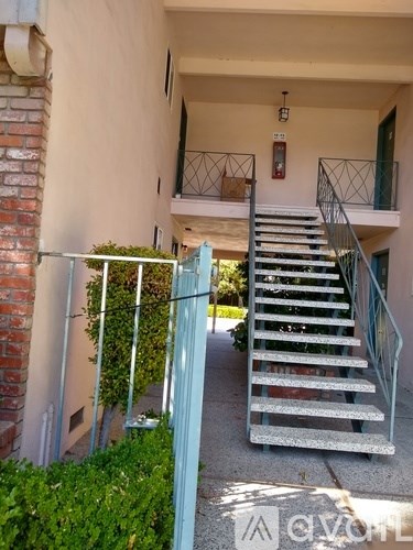 A staircase with a metal railing leads to a balcony.