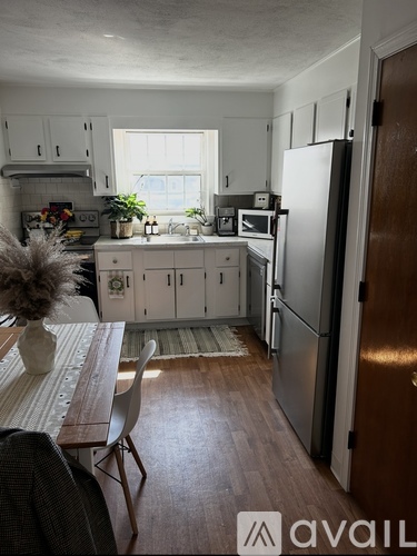 A kitchen with a refrigerator, sink, and dining table.