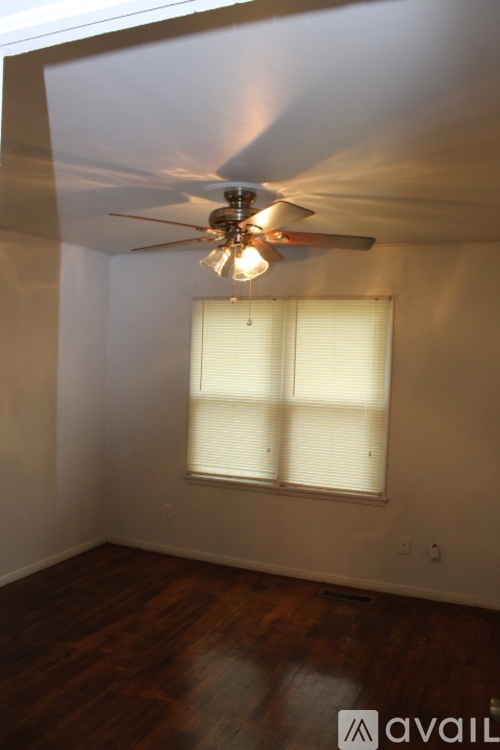 A room with a ceiling fan and a window with blinds.