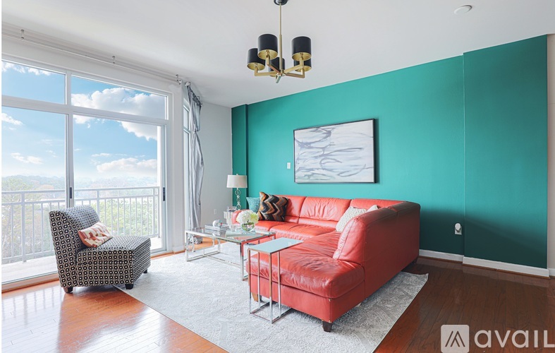A living room with a red couch and a chair with a view of the sky.