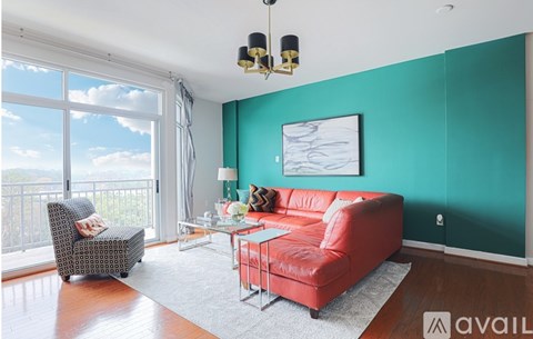 A living room with a red couch and a chair with a view of the sky.