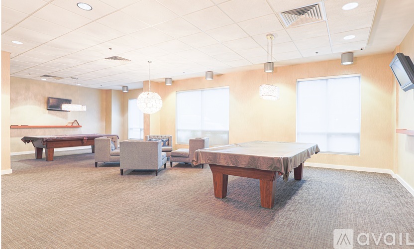 A spacious room with a billiard table, chairs, and a television.