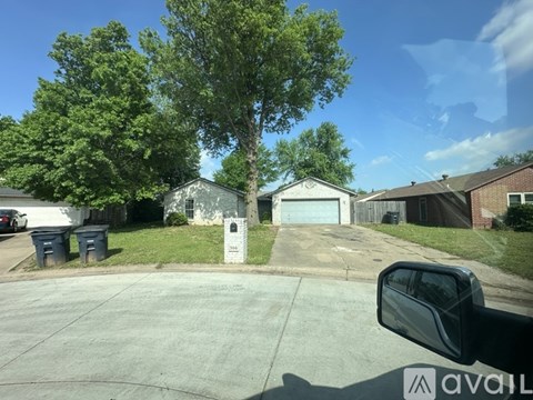 A car is parked in a driveway with a house and trees in the background.