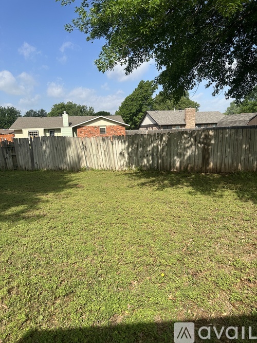 A backyard with a wooden fence and a house in the background.