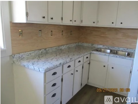 A kitchen with white cabinets and a marble countertop.