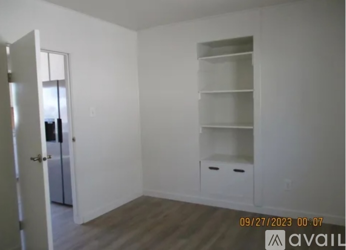 A room with a door, a shelf, and a wall socket.