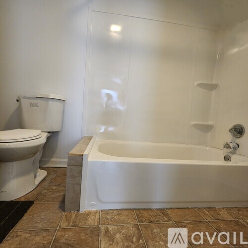 A white toilet sits next to a white bathtub in a bathroom.