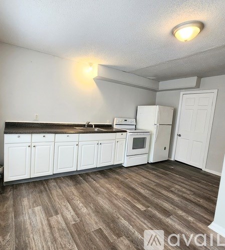 A kitchen with white cabinets and a wooden floor.
