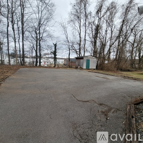 A large, empty parking lot surrounded by trees and a small building.