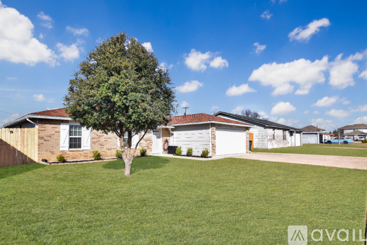 A tree stands in a grassy yard in front of a house.