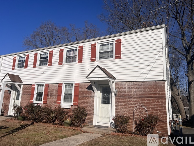 A house with a white siding and red brick chimney is for sale.