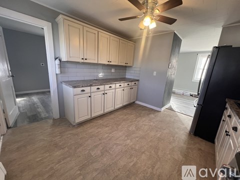 A kitchen with a fan on the ceiling and a black refrigerator.