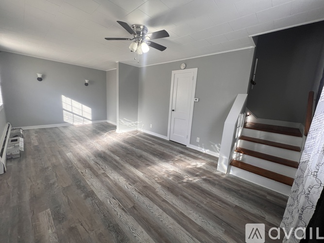 A room with a ceiling fan and wooden flooring.